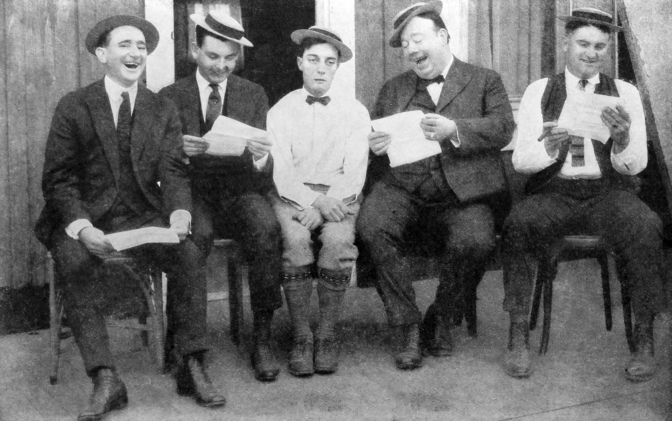 Old photo of men laughing at lone writer.