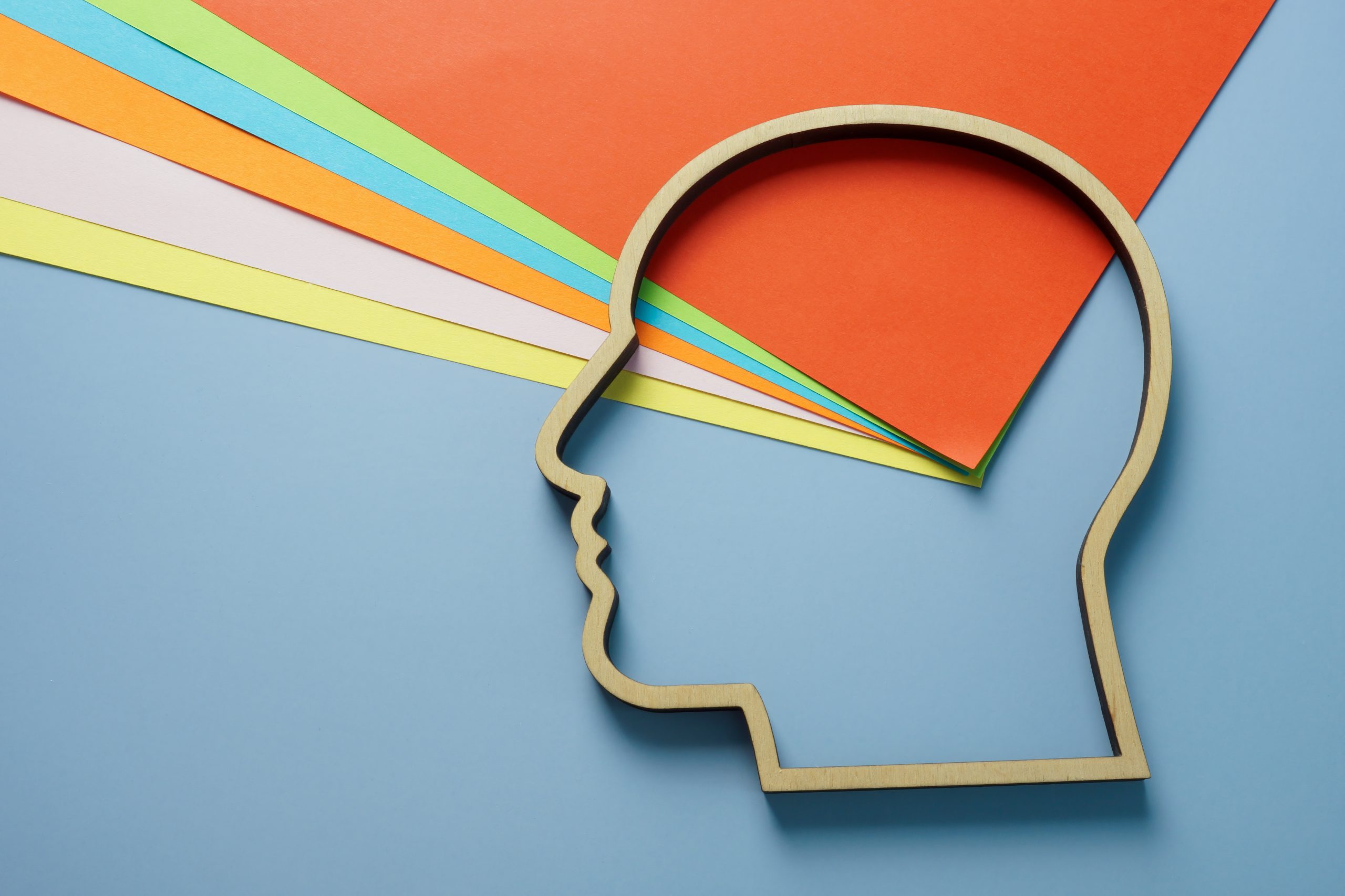Head outline and colored paper as symbol of creativity and neurodiversity.