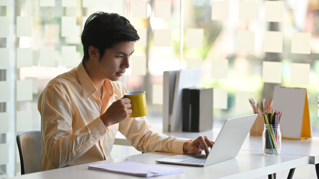Man using computer and drinking tea