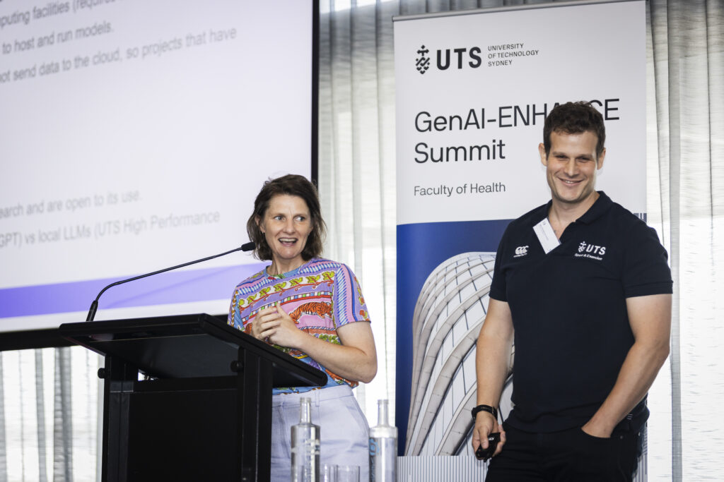 Katie Slattery and Steven Hughes present in front of GenAI-ENHANCE sign